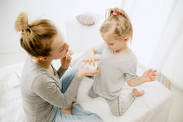 Image showing Young mother and her little daughter hugging and kissing on bed