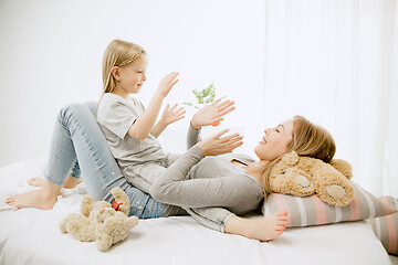 Image showing Young mother and her little daughter hugging and kissing on bed