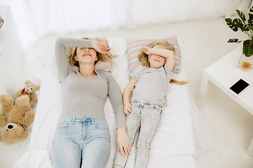 Image showing Young mother and her little daughter hugging and kissing on bed