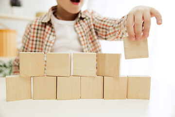 Image showing Little child sitting on the floor. Pretty boy palying with wooden cubes at home