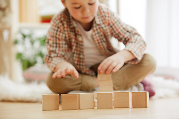 Image showing Little child sitting on the floor. Pretty boy palying with wooden cubes at home