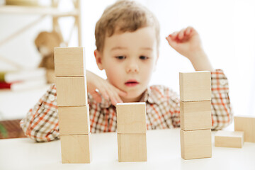 Image showing Little child sitting on the floor. Pretty boy palying with wooden cubes at home