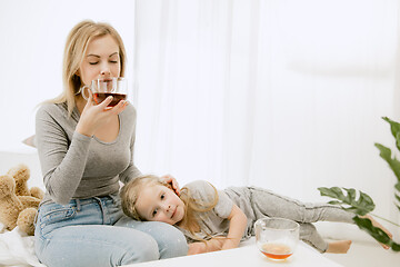 Image showing Young mother and her little daughter hugging and kissing on bed