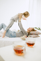 Image showing Young mother and her little daughter hugging and kissing on bed