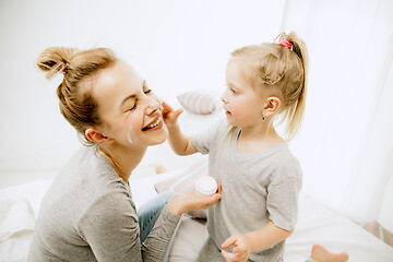 Image showing Young mother and her little daughter hugging and kissing on bed