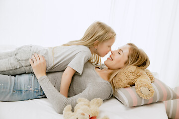 Image showing Young mother and her little daughter hugging and kissing on bed