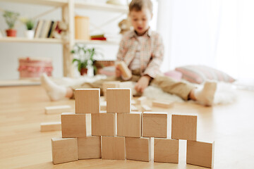 Image showing Little child sitting on the floor. Pretty boy palying with wooden cubes at home