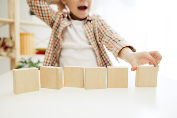 Image showing Little child sitting on the floor. Pretty boy palying with wooden cubes at home