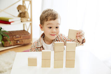 Image showing Little child sitting on the floor. Pretty boy palying with wooden cubes at home