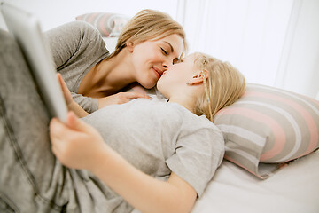 Image showing Young mother and her little daughter hugging and kissing on bed