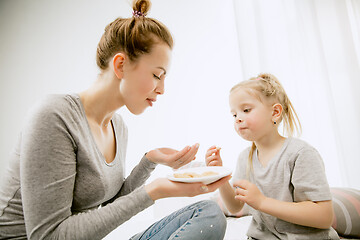 Image showing Young mother and her little daughter hugging and kissing on bed