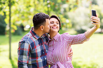 Image showing happy couple in park taking selfie by smartphone