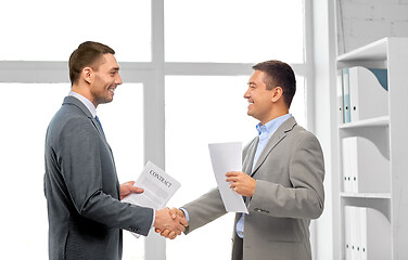 Image showing happy businessmen making handshake at office