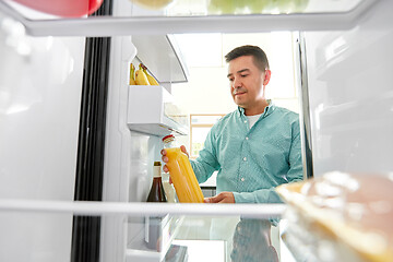 Image showing man taking juice from fridge at home kitchen