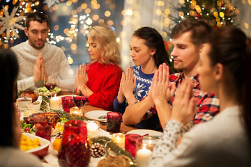Image showing friends having home christmas dinner and praying