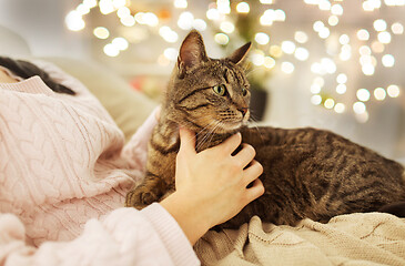 Image showing close up of owner with tabby cat in bed at home