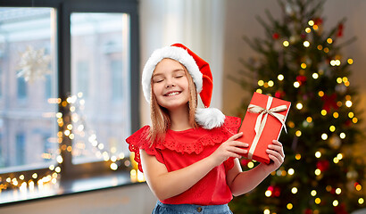 Image showing girl in santa hat with christmas gift at home