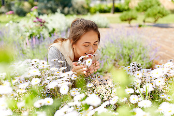 Image showing happy woman smelling chamomile flowers in garden