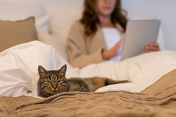 Image showing tabby cat lying in bed with woman at home bedroom