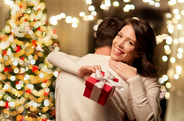 Image showing happy couple with christmas gift hugging at home