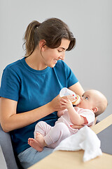 Image showing mother feeding baby daughter with milk formula