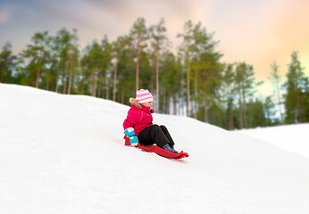 Image showing happy little girl sliding down on sled in winter