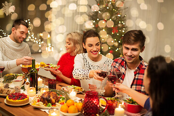 Image showing happy friends drinking red wine at christmas party