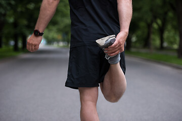 Image showing male runner warming up and stretching before morning training