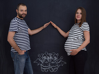 Image showing pregnant couple drawing their imaginations on chalk board