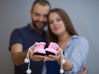 Image showing pregnant couple holding newborn baby shoes