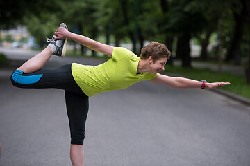 Image showing female runner warming up and stretching before morning training