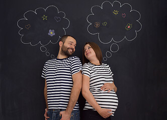 Image showing pregnant couple posing against black chalk drawing board