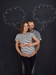 Image showing pregnant couple posing against black chalk drawing board