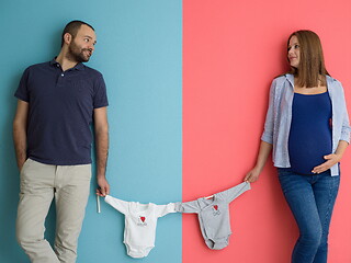 Image showing young couple holding baby bodysuits