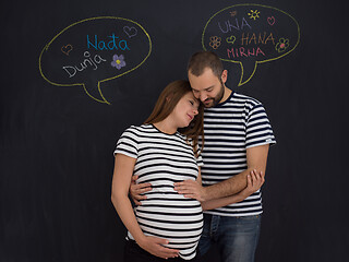 Image showing pregnant couple posing against black chalk drawing board