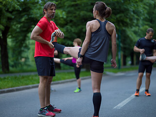 Image showing runners team warming up and stretching before morning training