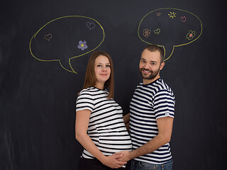 Image showing pregnant couple posing against black chalk drawing board