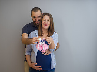 Image showing pregnant couple holding newborn baby shoes