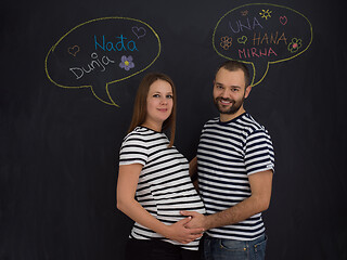 Image showing pregnant couple posing against black chalk drawing board