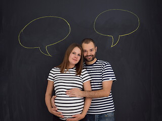 Image showing pregnant couple posing against black chalk drawing board