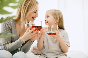 Image showing Young mother and her little daughter hugging and kissing on bed