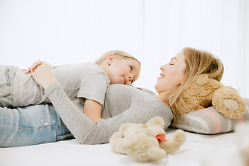 Image showing Young mother and her little daughter hugging and kissing on bed