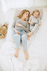 Image showing Young mother and her little daughter hugging and kissing on bed