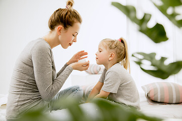 Image showing Young mother and her little daughter hugging and kissing on bed