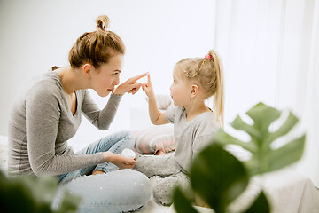 Image showing Young mother and her little daughter hugging and kissing on bed