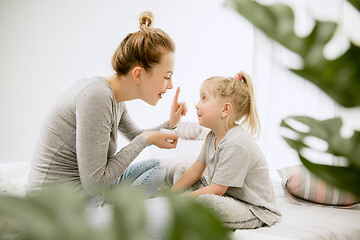 Image showing Young mother and her little daughter hugging and kissing on bed