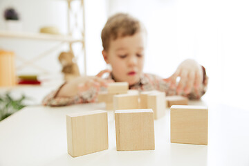 Image showing Little child sitting on the floor. Pretty boy palying with wooden cubes at home