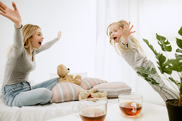 Image showing Young mother and her little daughter hugging and kissing on bed