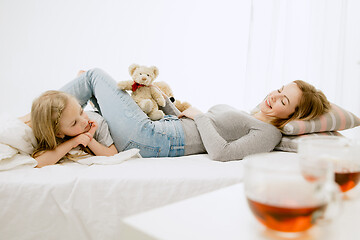 Image showing Young mother and her little daughter hugging and kissing on bed