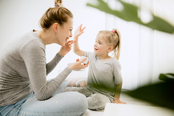 Image showing Young mother and her little daughter hugging and kissing on bed